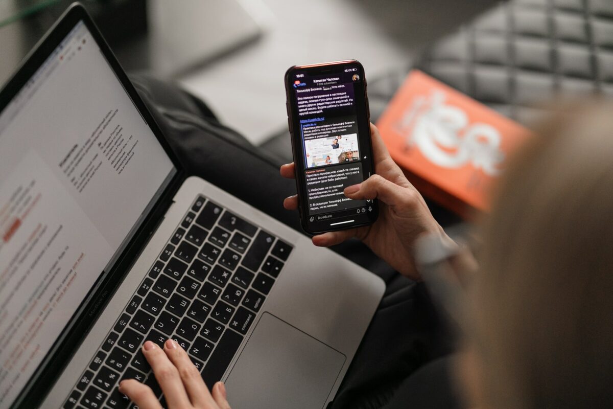 A woman holds a mobile phone and the laptop